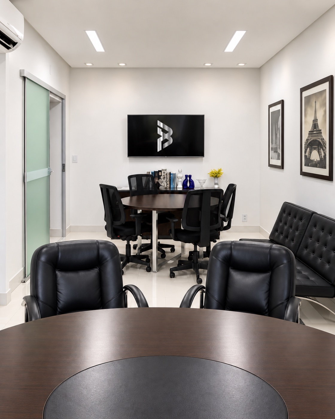 Sala de reunião do escritório Borges Perilo, com mesa redonda, poltronas e o monograma da marca na tela